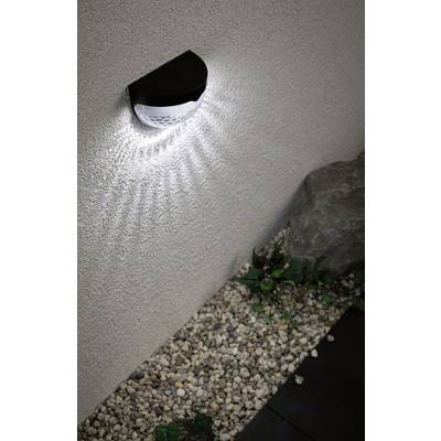 Wall light illuminates a stone wall and scatters light rays. Below, pebbles and a large stone are visible.