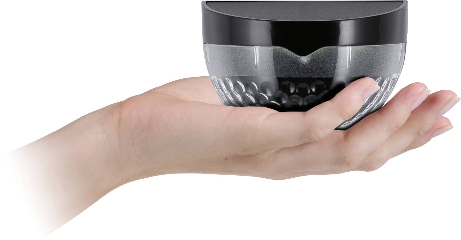 An open hand is holding a small round container with a black lid, which may be used for cosmetic products.