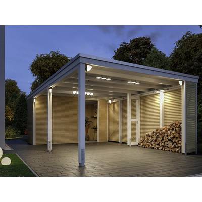 A modern car port with side wooden cladding, illuminated at night. A stack of wood is visible underneath the shelter on the left.