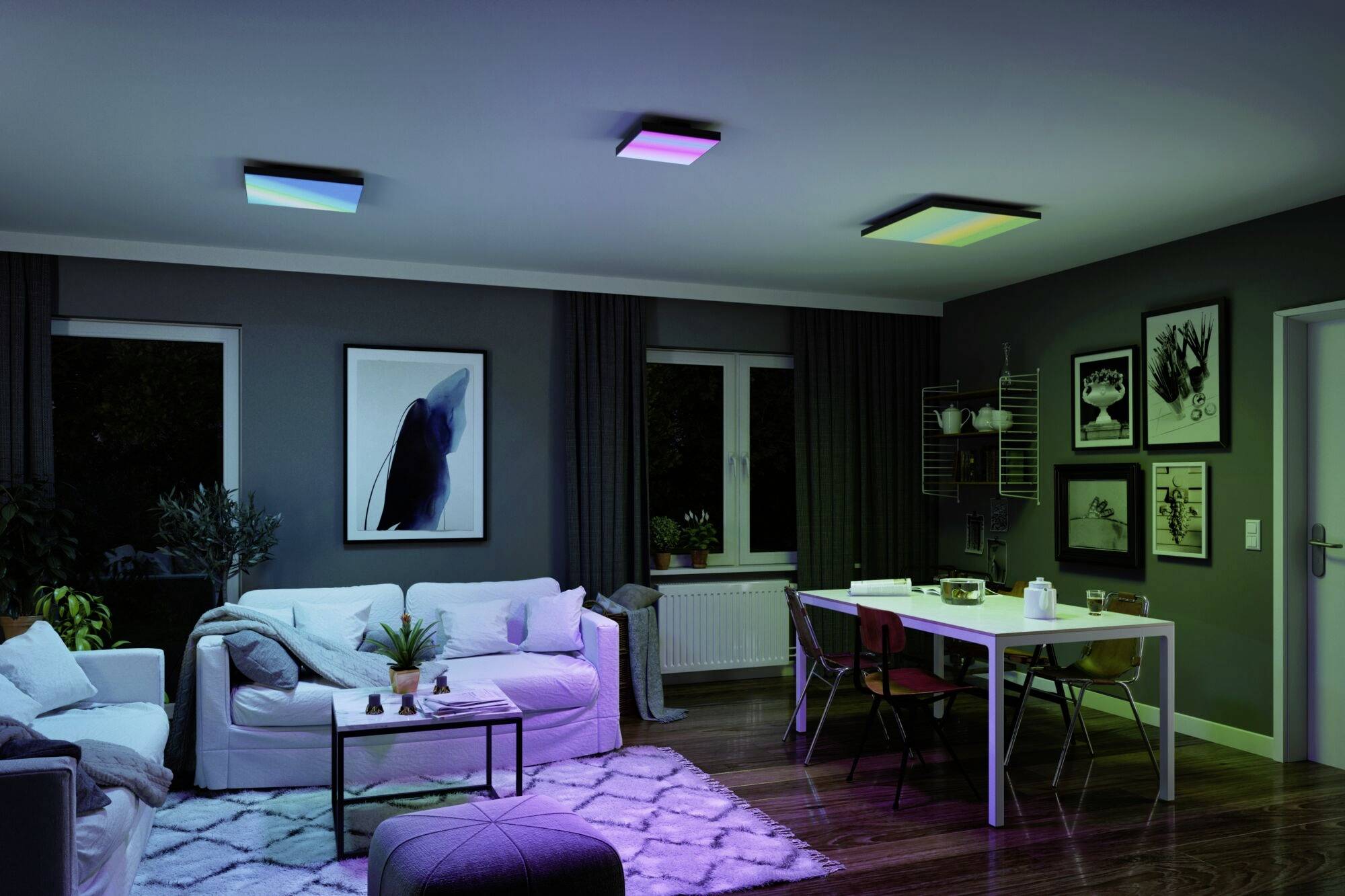 Living room with modern lighting, showcasing colour-changing ceiling lights. Bright sofa, table and decorative pictures on the wall.