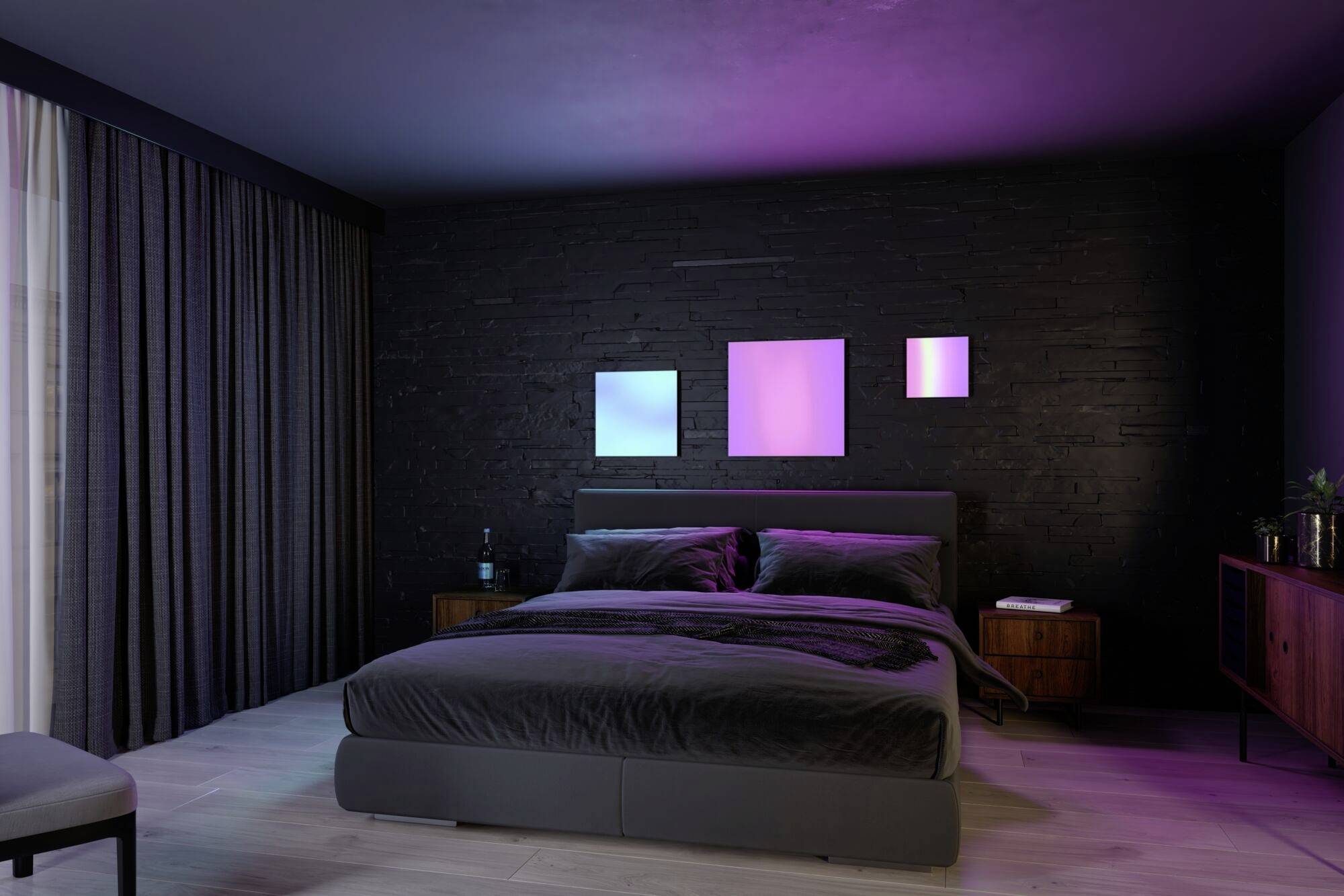 A modern bedroom with a large bed and three illuminated square wall artworks in blue and pink above the bed.