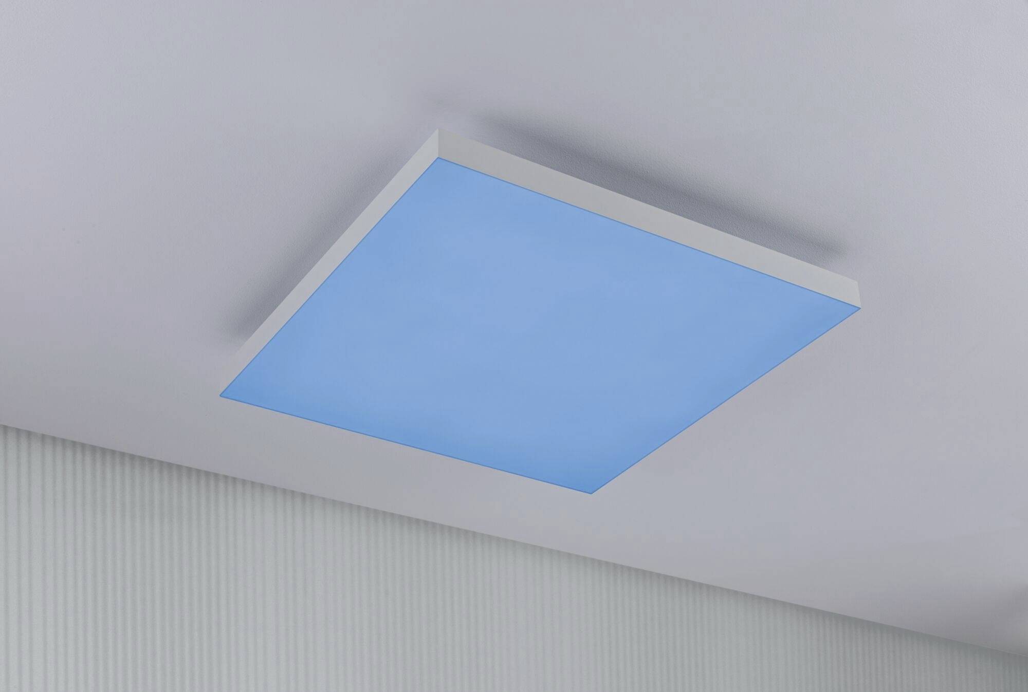 Blue light shining on the ceiling of a modern room.