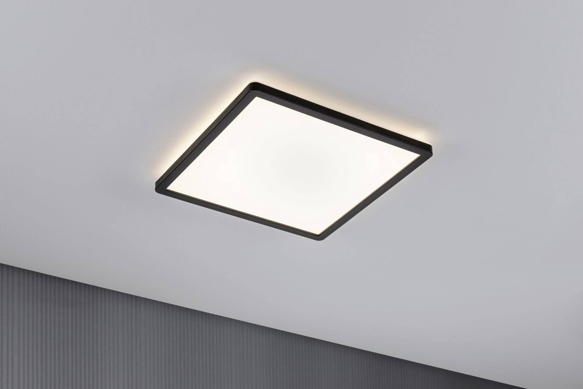 Square ceiling light with a matte frame, mounted on a white ceiling, emitting diffused light.