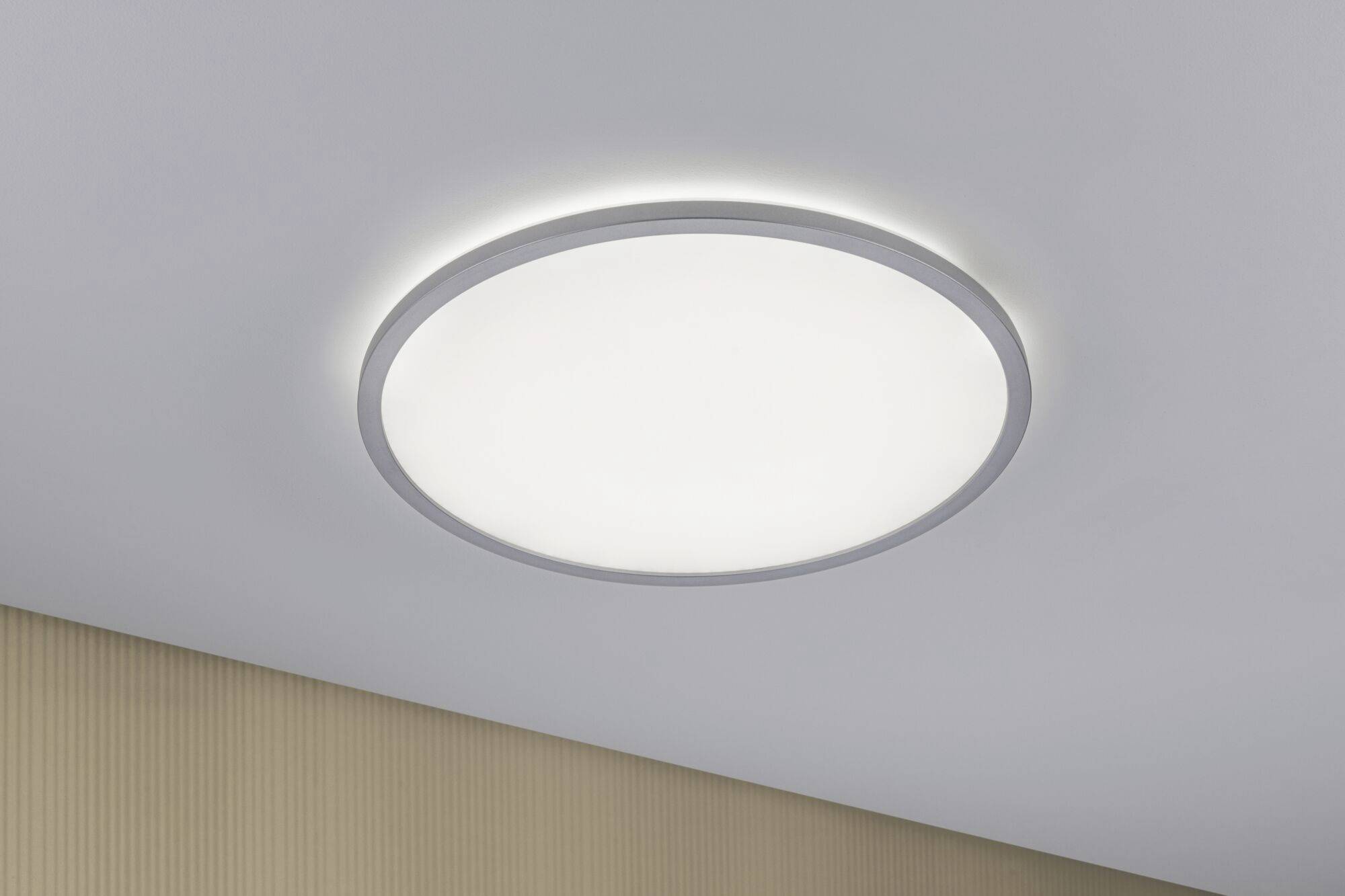 Round ceiling light, switched on, mounted on a white ceiling. It provides an even, diffused light in the room.