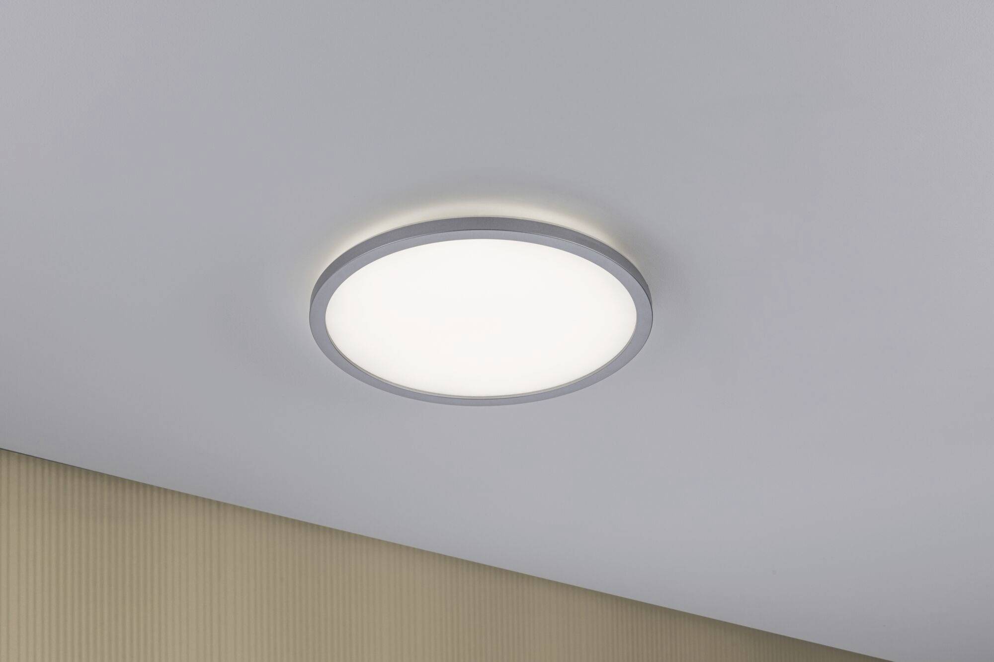Round ceiling light with matte frame mounted on a light grey ceiling, evenly illuminated.