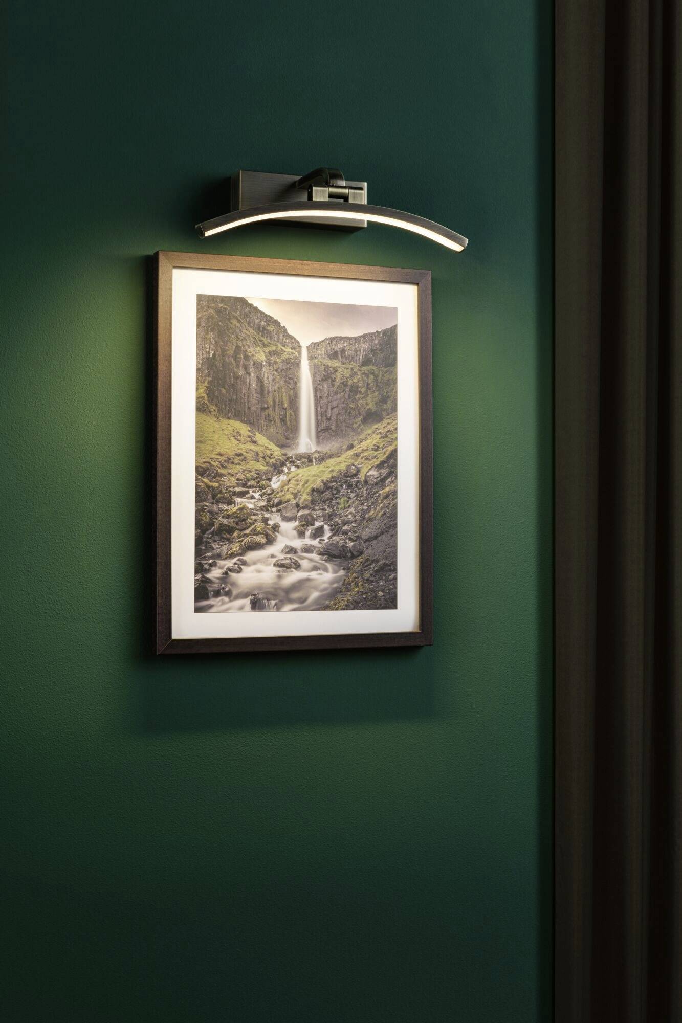 A lit picture on a green wall shows a tall waterfall flowing into a rocky river, surrounded by vegetation.