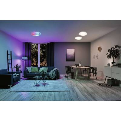 A modern furnished living room with colour-changing lighting. A sofa, a table, and various decorations can be seen.
