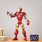 A red and golden toy robot in a superhero armour stands on a table. Next to it lies a small, black card.