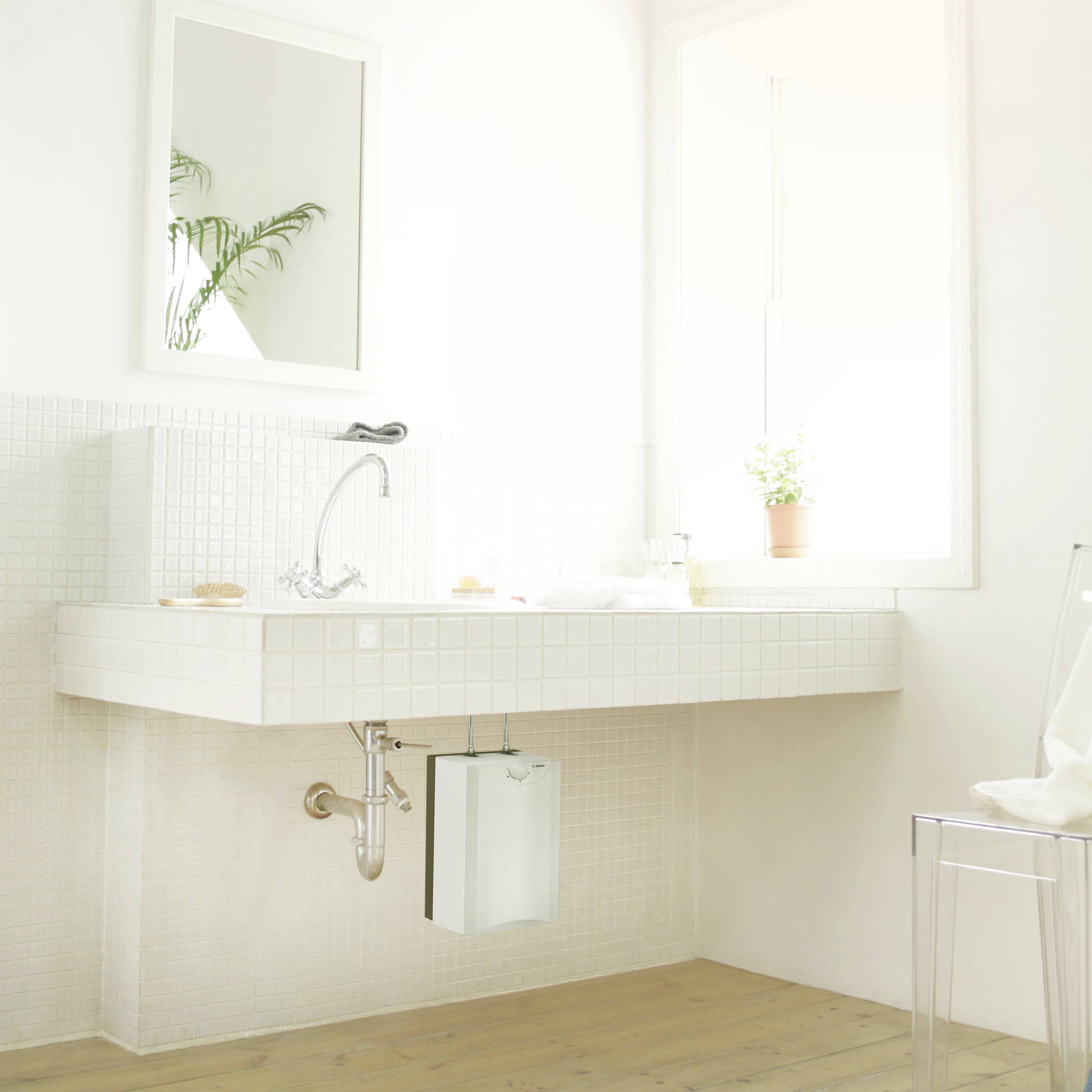 Bright bathroom with a large window, white washbasin and mirror. A plant can be seen in the background.