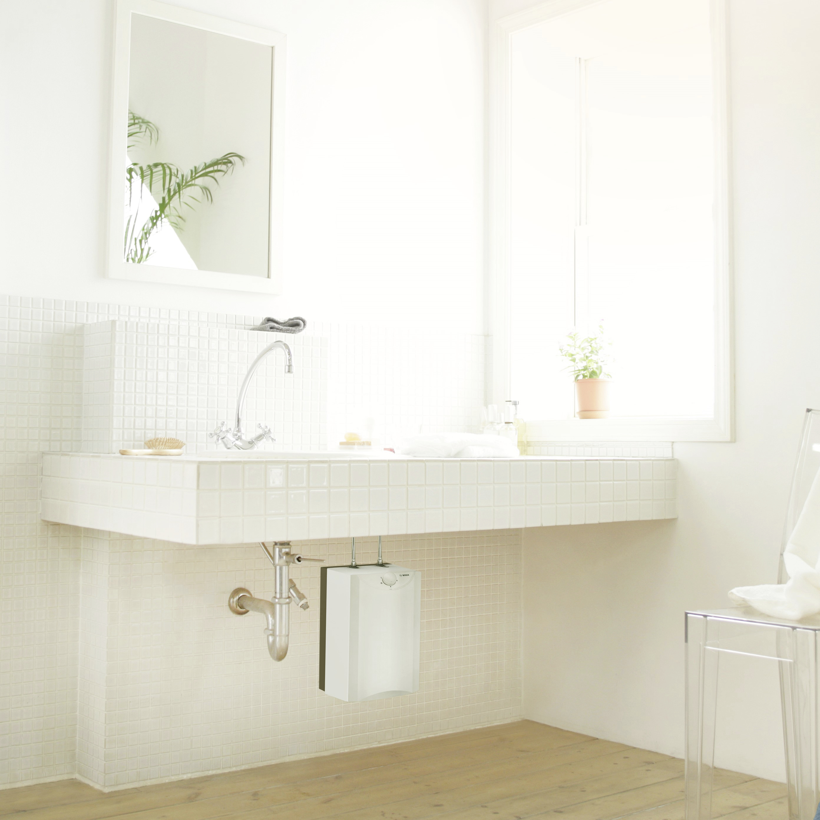 Bright bathroom with a large window, white washbasin and mirror. A plant can be seen in the background.