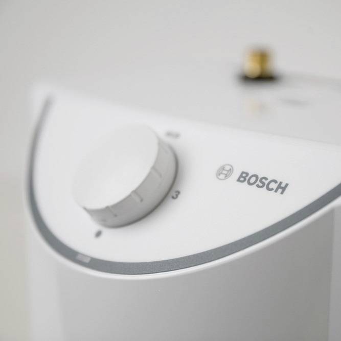 Close-up of a Bosch water heater with a rotary knob for temperature adjustment, shown in a neutral setting.