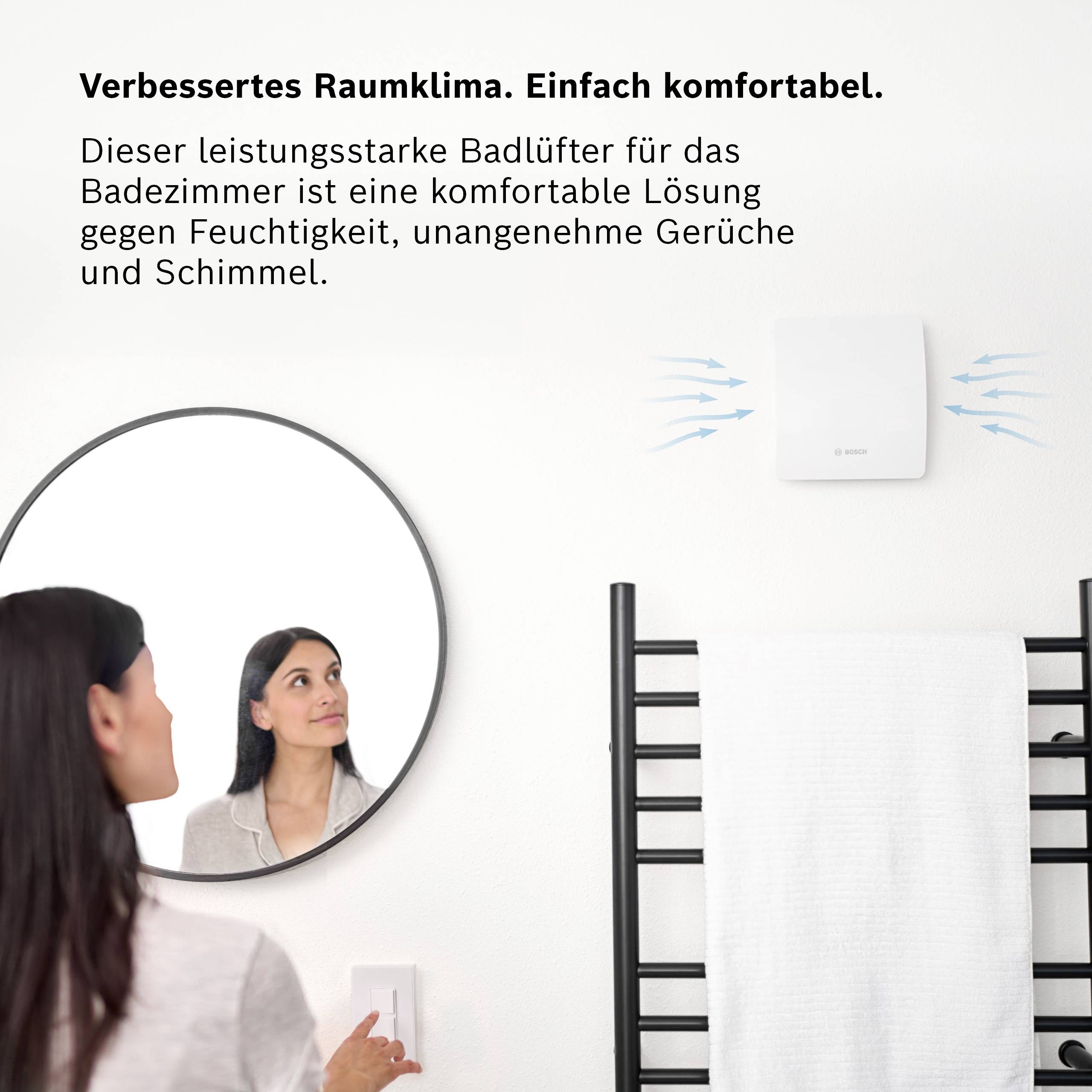 Woman in bathroom operating a ventilation switch. Text: 'Enhanced Indoor Climate. Simply Comfortable.'<br><br>Note: In British English advertising copy, this translation maintains the clean, concise style typical of product marketing language.