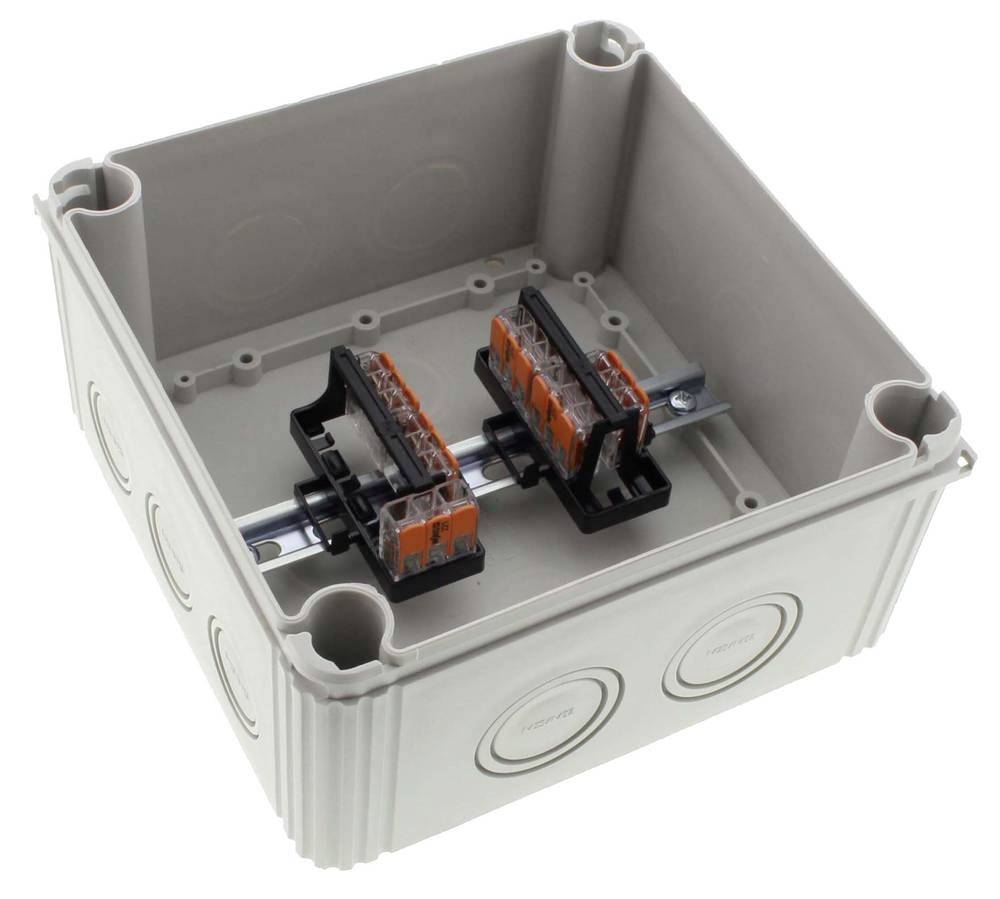 Grey, empty electrical junction box with two orange-black terminals mounted on a metal rail.