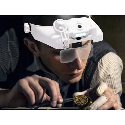 A person is wearing a magnifying glasses with LED light and is working intently on a small clockwork mechanism with a tool in hand.