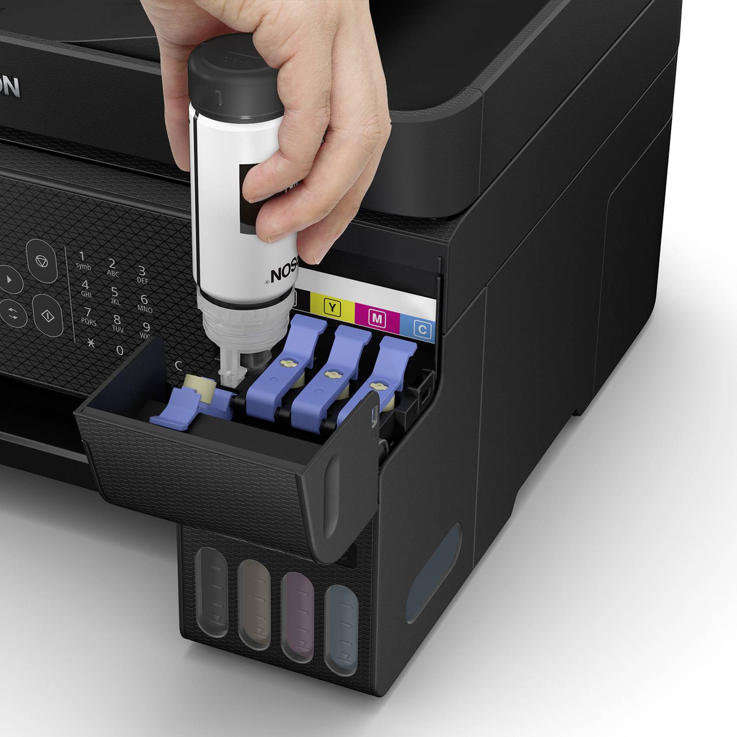 A hand fills an ink cartridge at a printer station. Colour-coded containers display Yellow, Magenta, Cyan and Black.