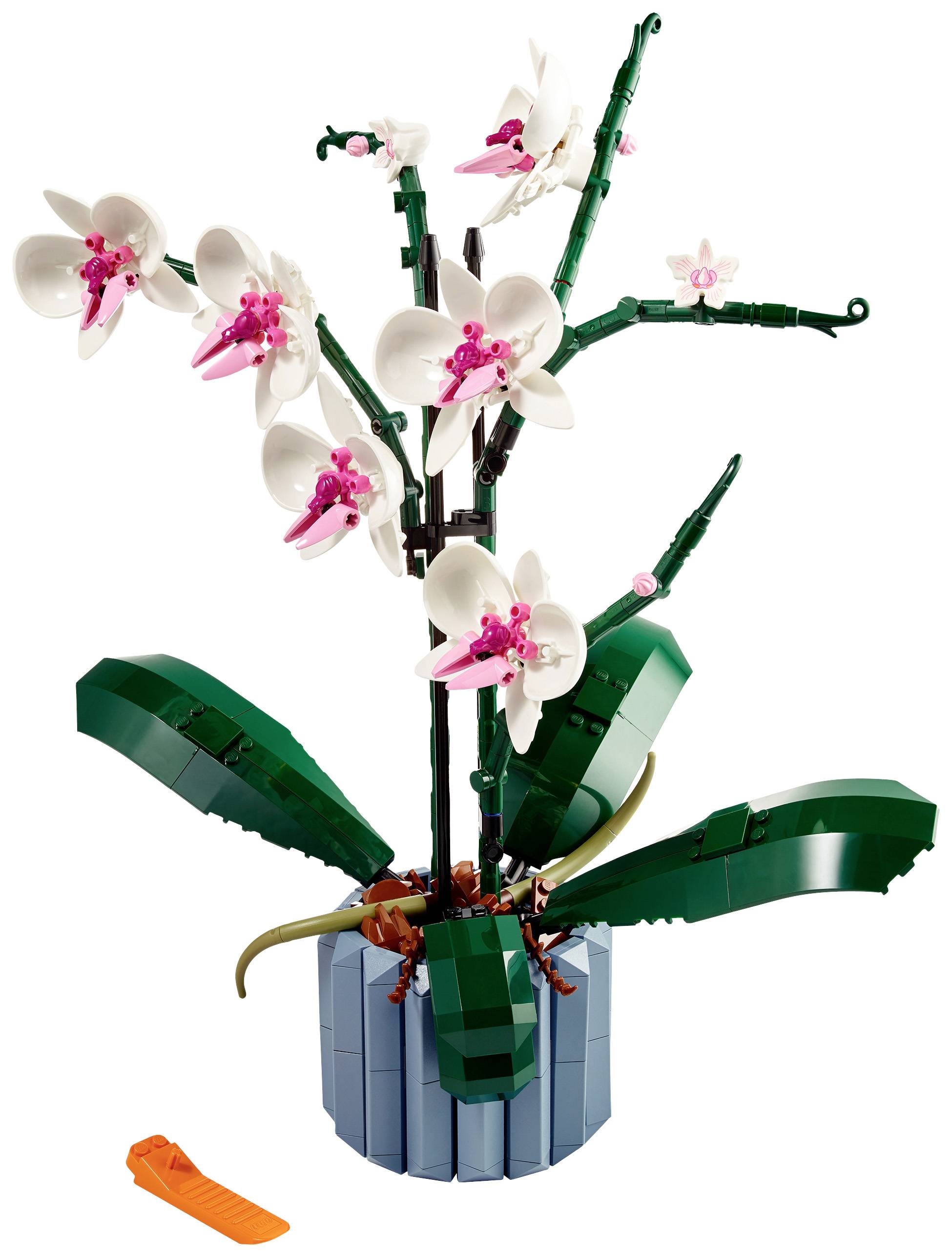 A model of a white orchid made from building blocks in a pot. The blossoms are intricately designed, with pink details and green leaves.