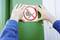 A person is attaching a prohibition sign with a crossed-out smoking symbol to a green wall.
