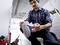 A man in a checked shirt is repairing an extension lead in an industrial space, surrounded by tools.