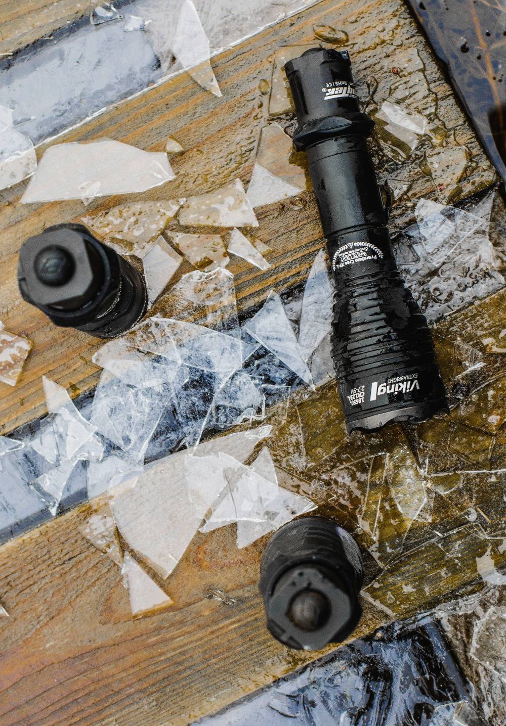 Broken glass lies on a wet wooden floor, surrounded by robust torches and bottles with muddy seals.