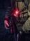 A person is holding a rifle in their right hand and has a red illuminating torch attached to their chest.