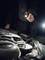 "A person is examining the engine compartment of a car at night using a torch."<br><br>Note: In British English, "flashlight" would be replaced with "torch", which is the standard term used in the UK.