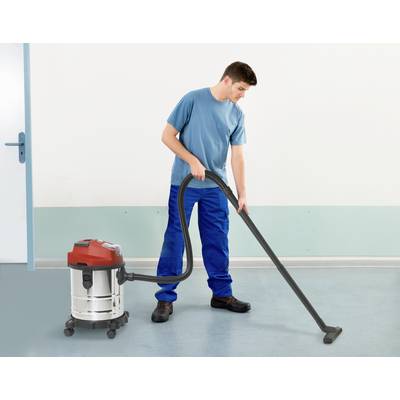 A man is cleaning the floor with an industrial vacuum cleaner in a room with blue walls and a light-coloured floor.