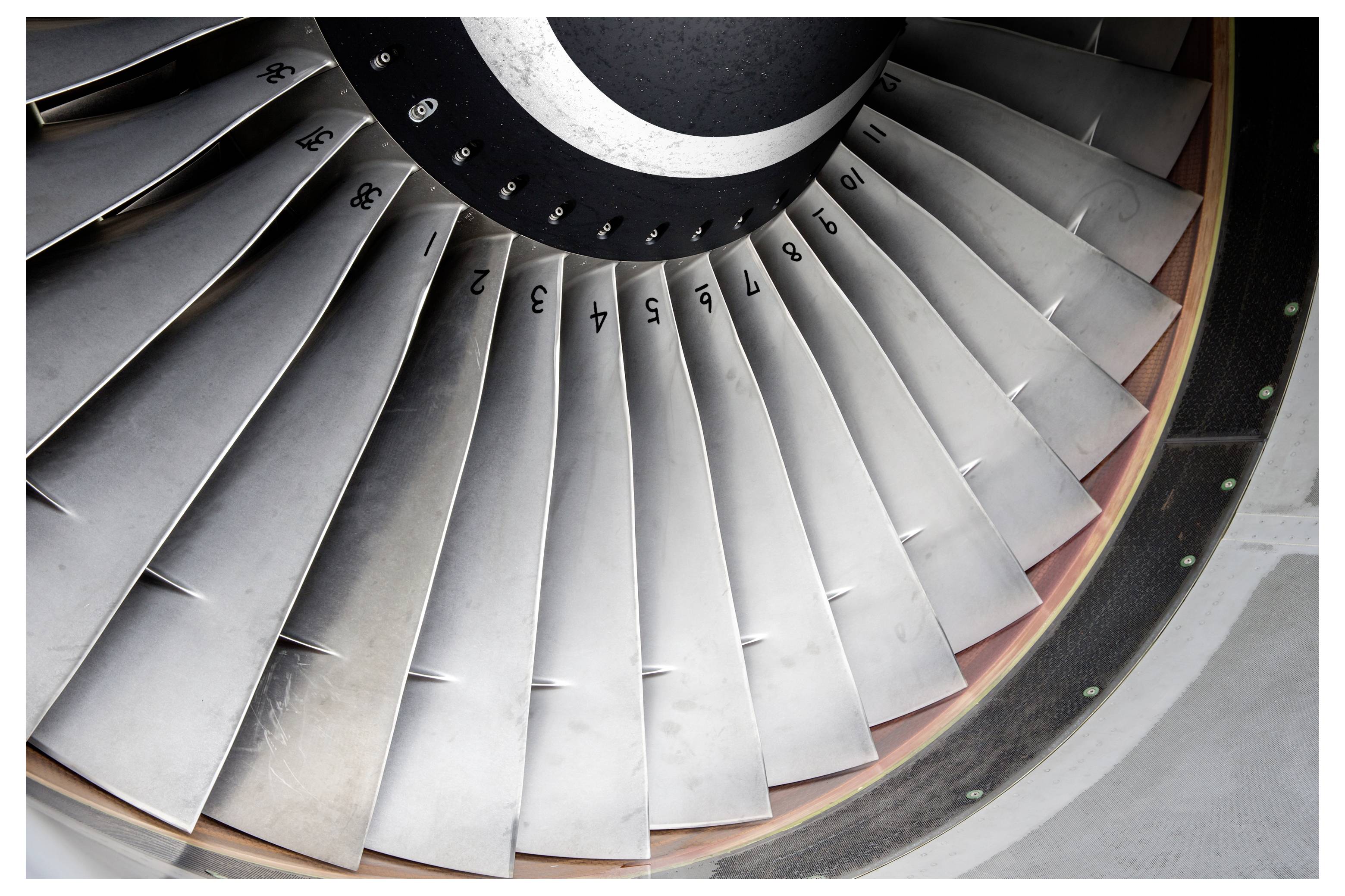 Close-up of a jet engine fan turbine with numbered metal blades<br>