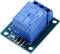 A blue relay module with three pins mounted on a green printed circuit board, used for controlling electrical circuits.