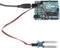 Pictured is an Arduino UNO board with a moisture sensor, connected by cables. It is used for measuring soil moisture.
