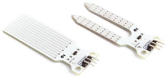 Two moisture sensors made of white material, one in a flat rectangular shape and one in a forked version, each with metal contacts.