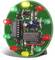 A round green circuit board featuring several red, green, and yellow LEDs along with two integrated circuits.