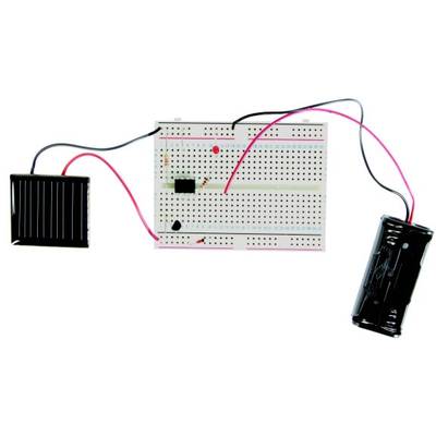 'Circuit on a breadboard with a solar panel and a battery holder, connected by wires. A red LED light is visible in the centre.'