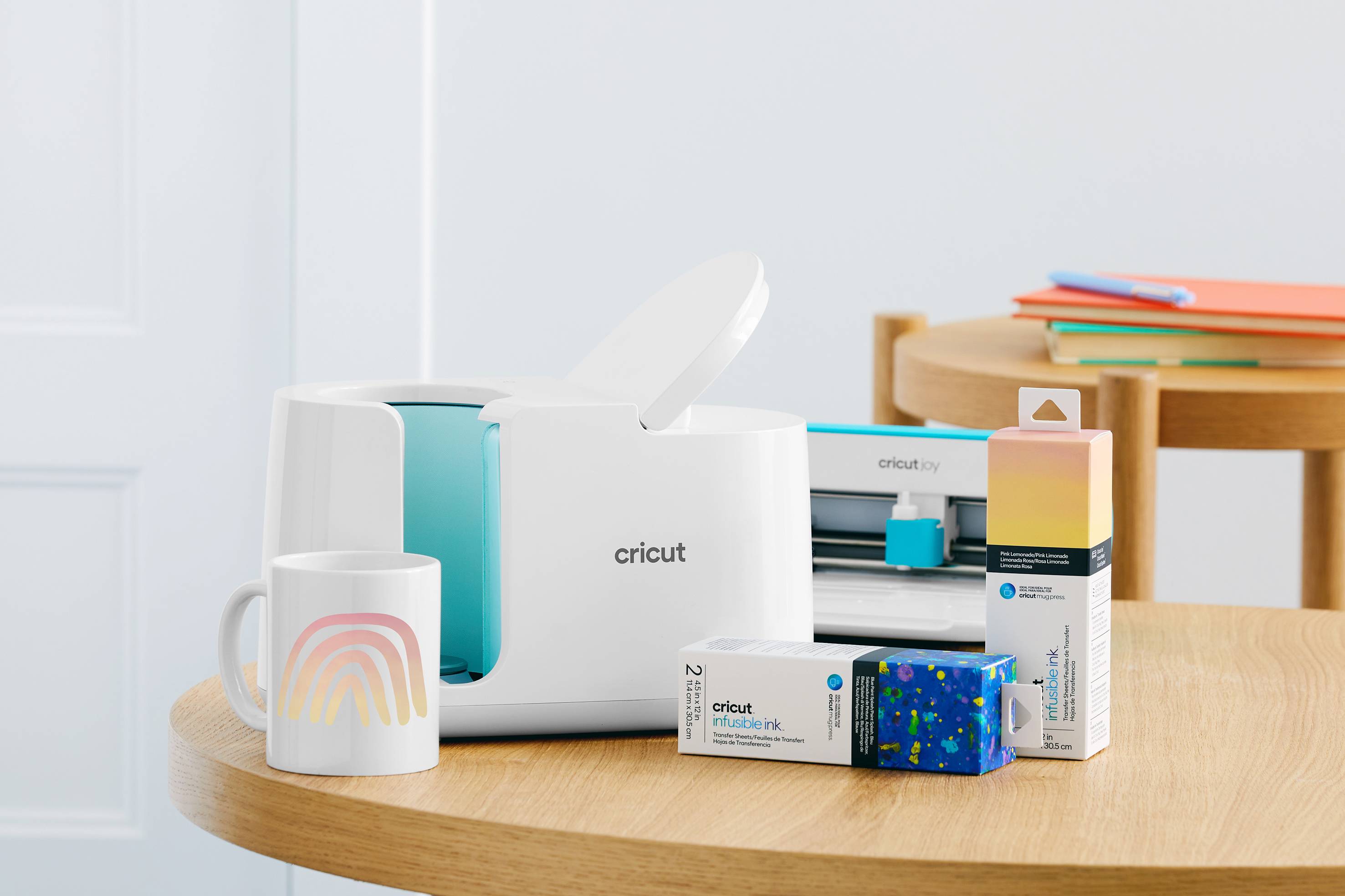 A Cricut cutting machine sits on a table next to packaged materials, such as vinyl and crafting tools.