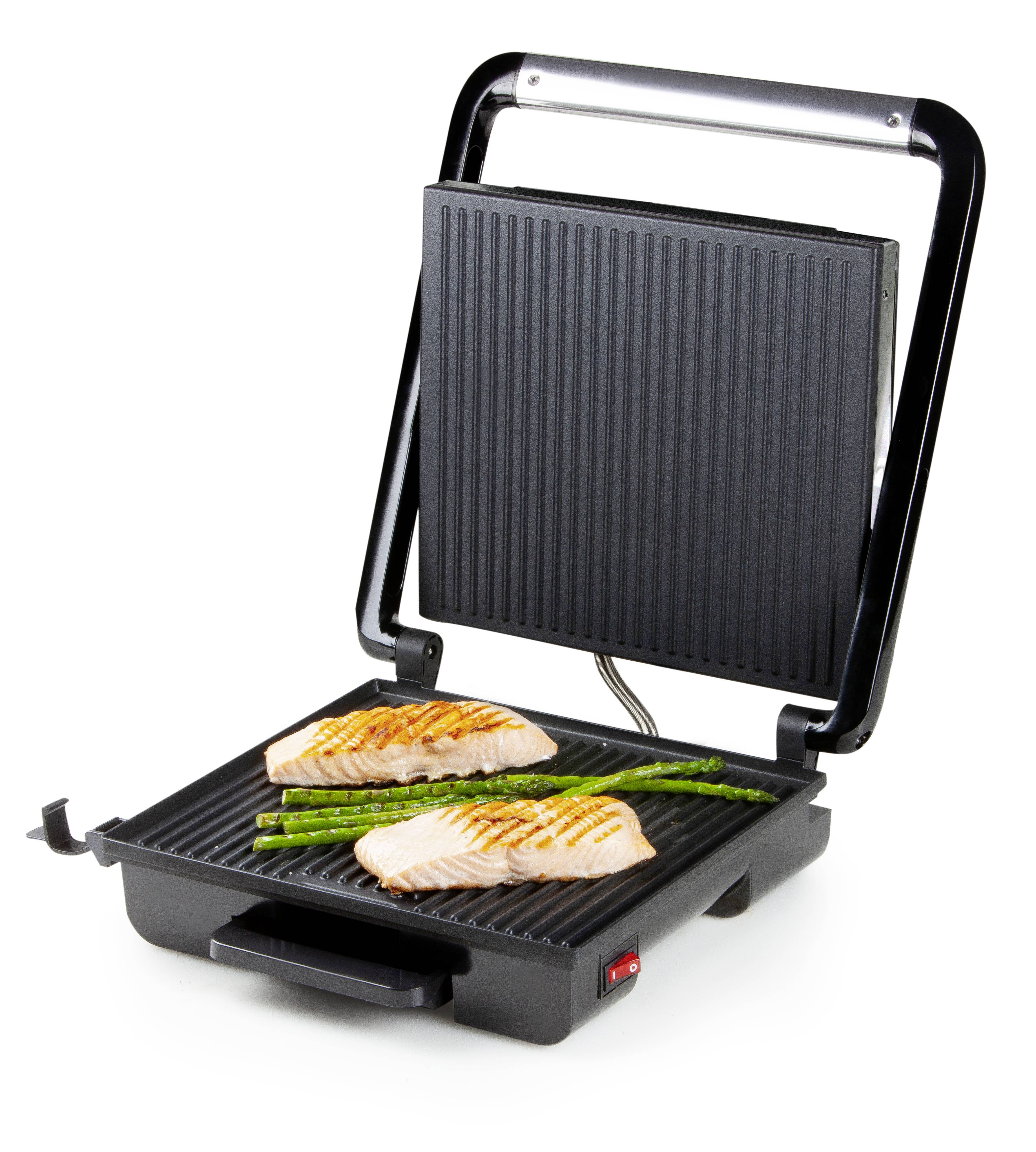 Electric tabletop grill with the grill plate opened up. Two pieces of salmon and asparagus are being grilled on it.