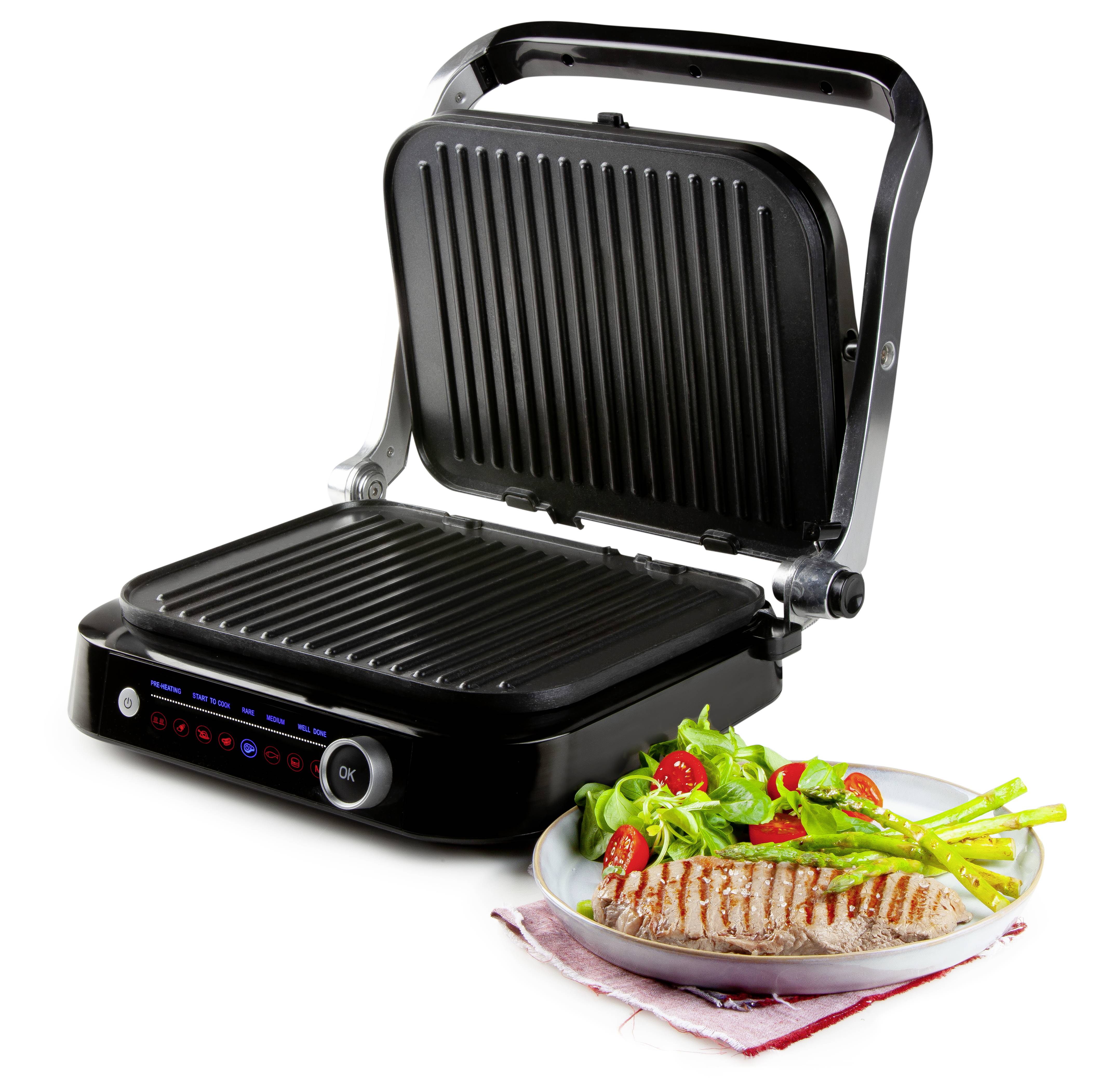 An open electric barbecue next to a plate with grilled chicken breast fillet, asparagus, and salad.