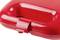 A red plastic handle with a glossy surface, possibly part of a suitcase or device, shown in close-up.