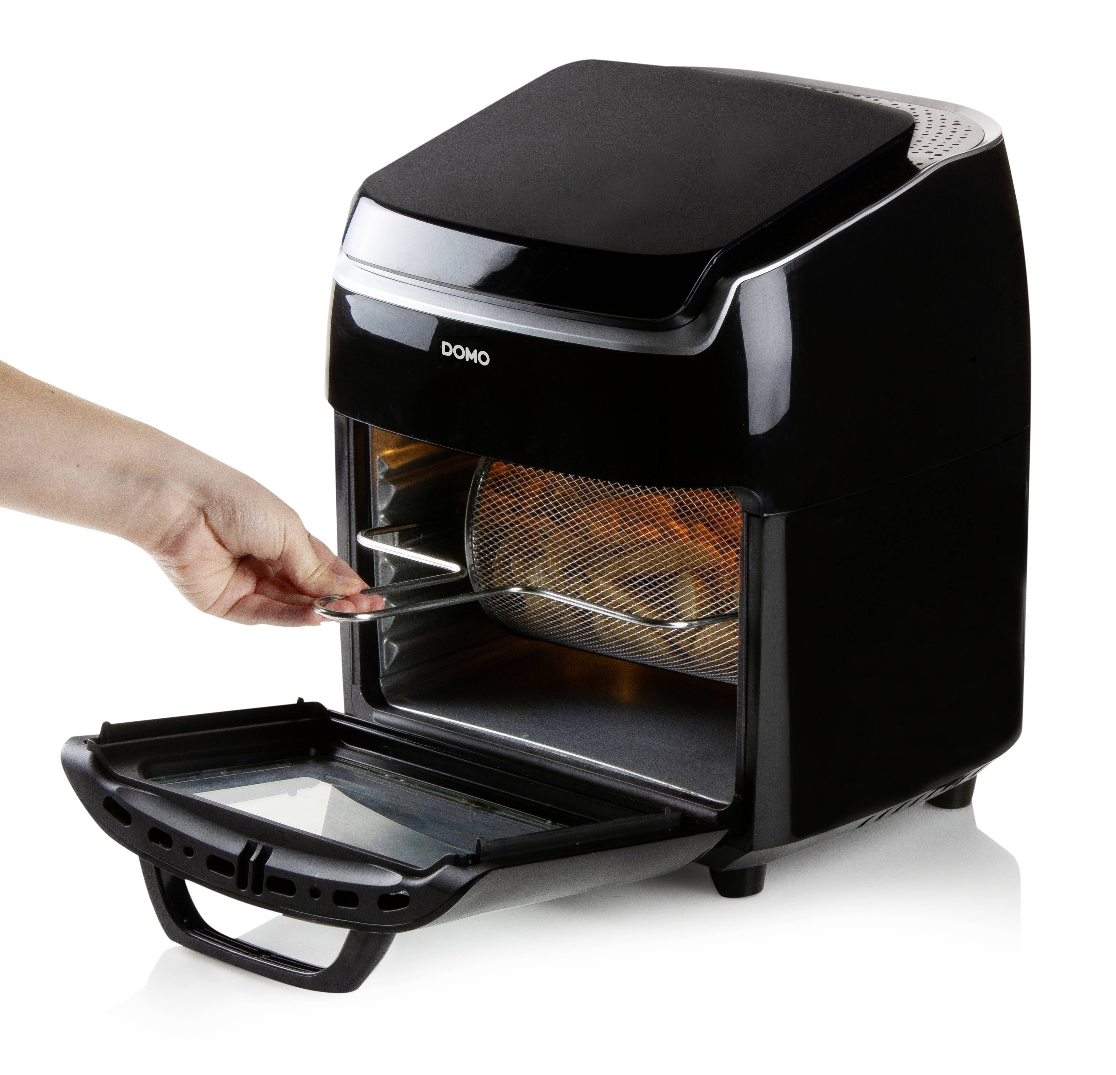 Compact hot air oven with the door open. A hand is pulling out the grill, suitable for oil-free frying.