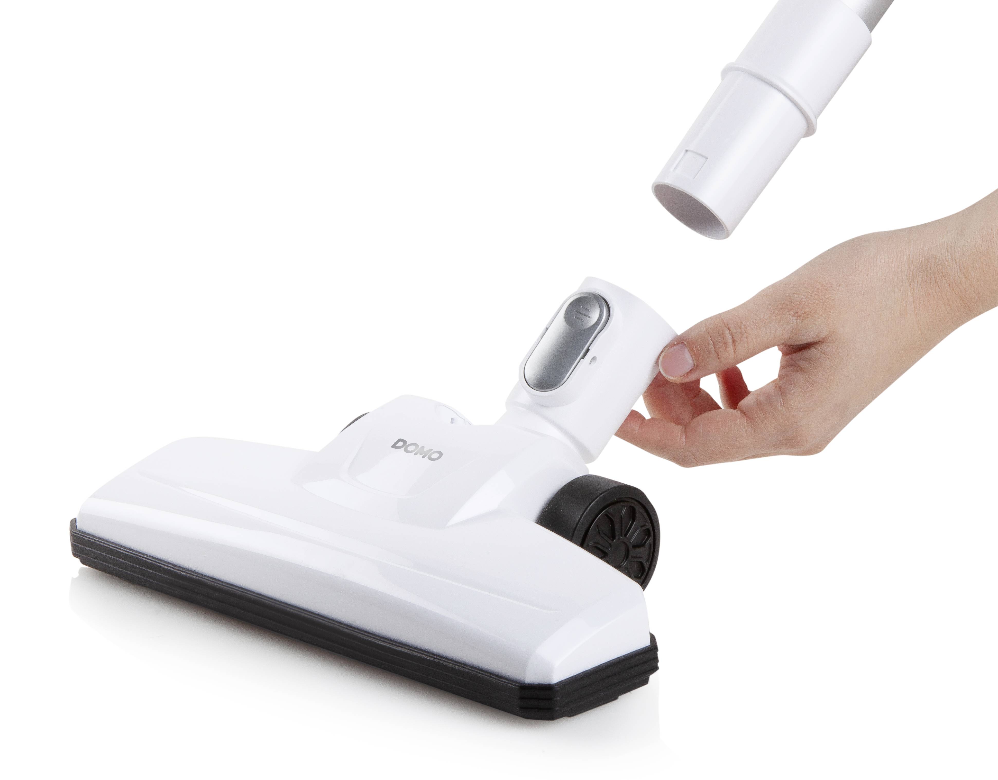 A hand is inserting a pipe into the connection of a white vacuum cleaner head. The vacuum cleaner head has wheels and a floor brush.