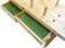 Wooden table with green velvet drawers pulled out. Table legs pointing upwards. Back of a measuring tape visible.