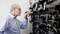 An older gentleman carefully inspects a large shelf of digital cables and devices, potentially in a technical environment.