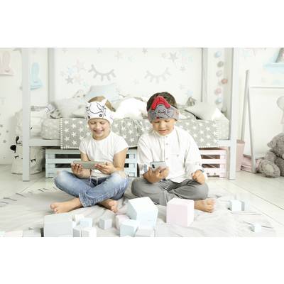 Two children are sitting on the floor and playing with smartphones. They are wearing headwear with animal motifs. Background: a child-decorated room.