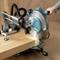 A circular saw is cutting a wooden board. The saw is manually guided and is positioned against a wooden background.