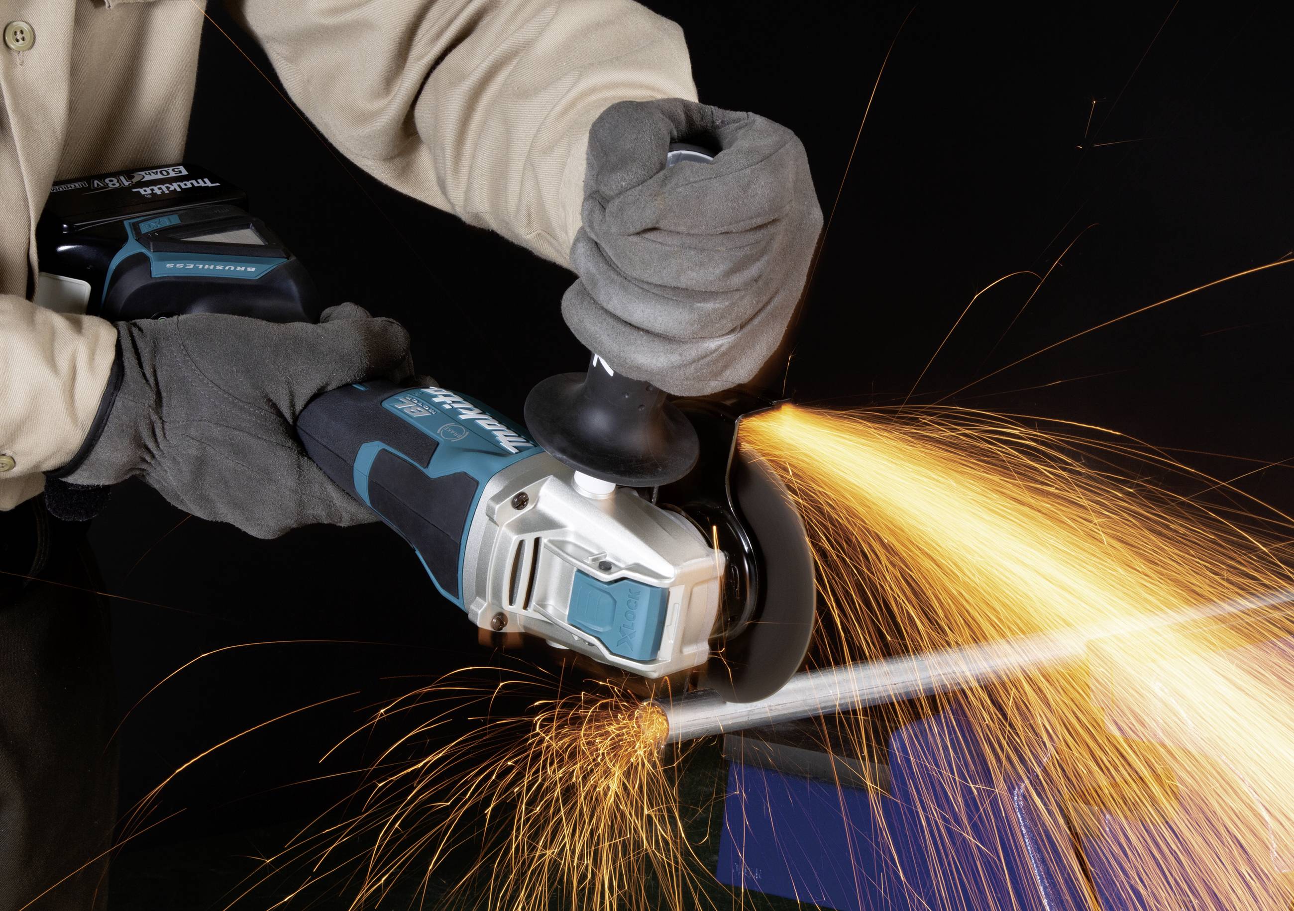 A person is using an angle grinder, with sparks flying. They are wearing work gloves.