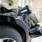 A person is using a cordless impact wrench to loosen a wheel nut on a car tyre.