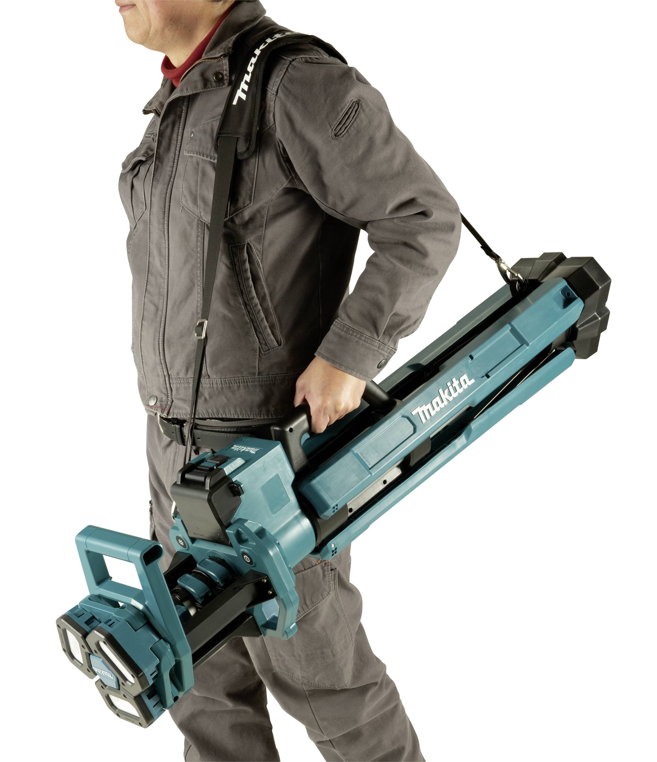 A person is carrying a folded, portable Makita site light over their shoulder.