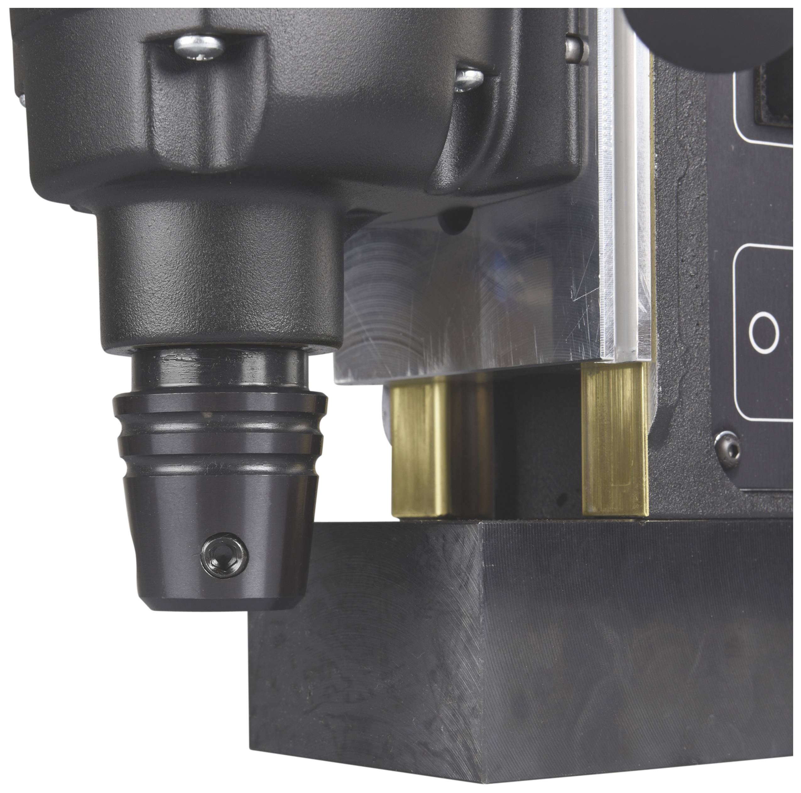 Close-up of a black industrial machine with metallic and gold-coloured elements. It appears to be precision-engineered.