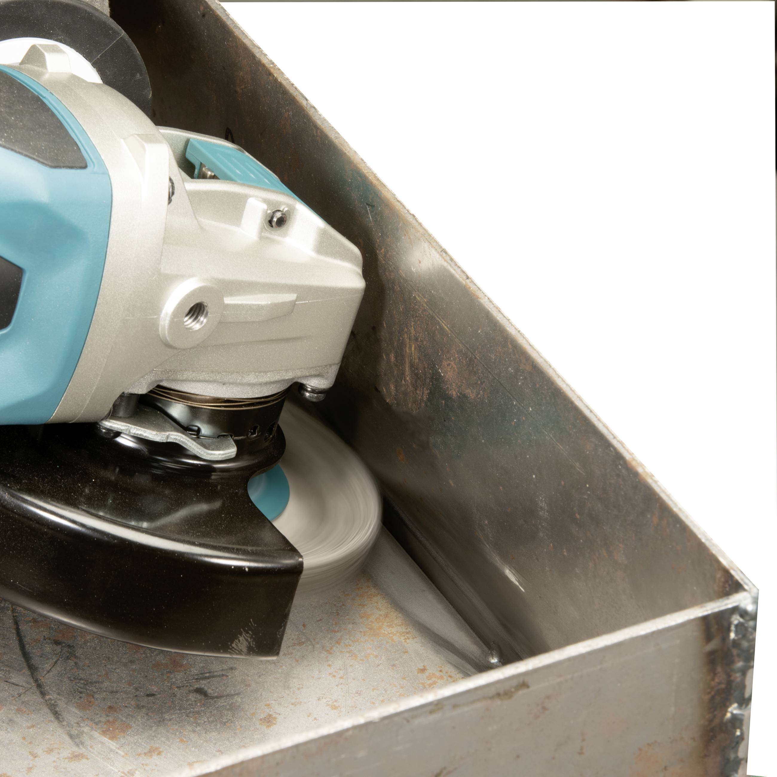 An angle grinder cuts metal inside a rectangular container. Sparks are visible due to the cutting process.