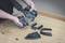 'A person is holding parts of an electric power tool on a wooden table. Workbench work with various removable machine components.'