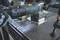 A person is using an electric tool to work on metal on a workbench. There are metal shavings on the table surface.