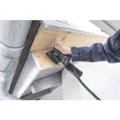 A person is sanding a wooden cladding beneath an eaves overhang using an electric power tool. The tool is black and green.